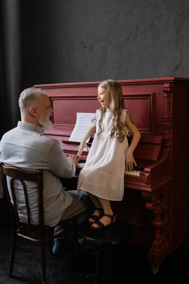 Grandfather And Granddaughter Laughing While Looking At Each Other