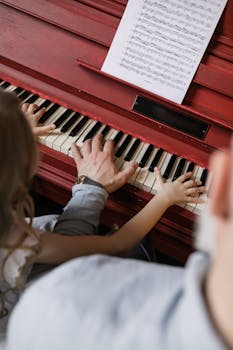 A grandfather and granddaughter bond while playing the piano, highlighting family togetherness.