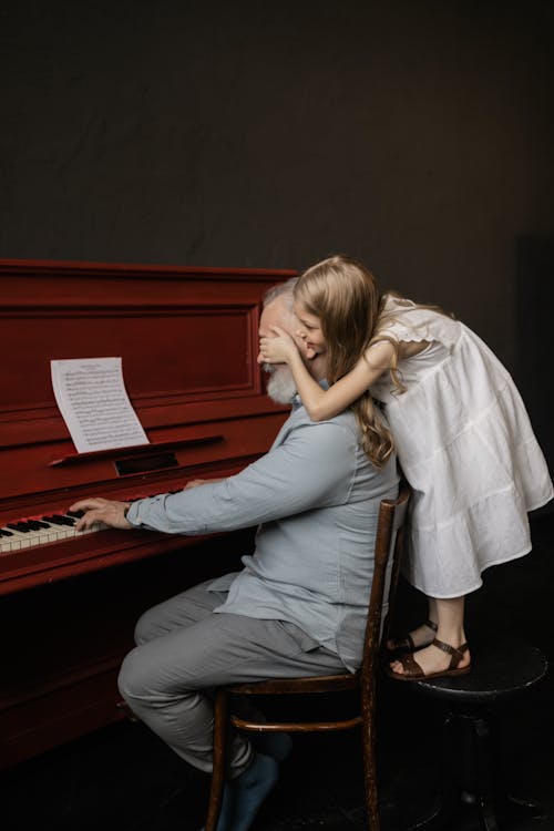 Granddaughter Covering Her Grandfather's Eyes while Playing the Piano
