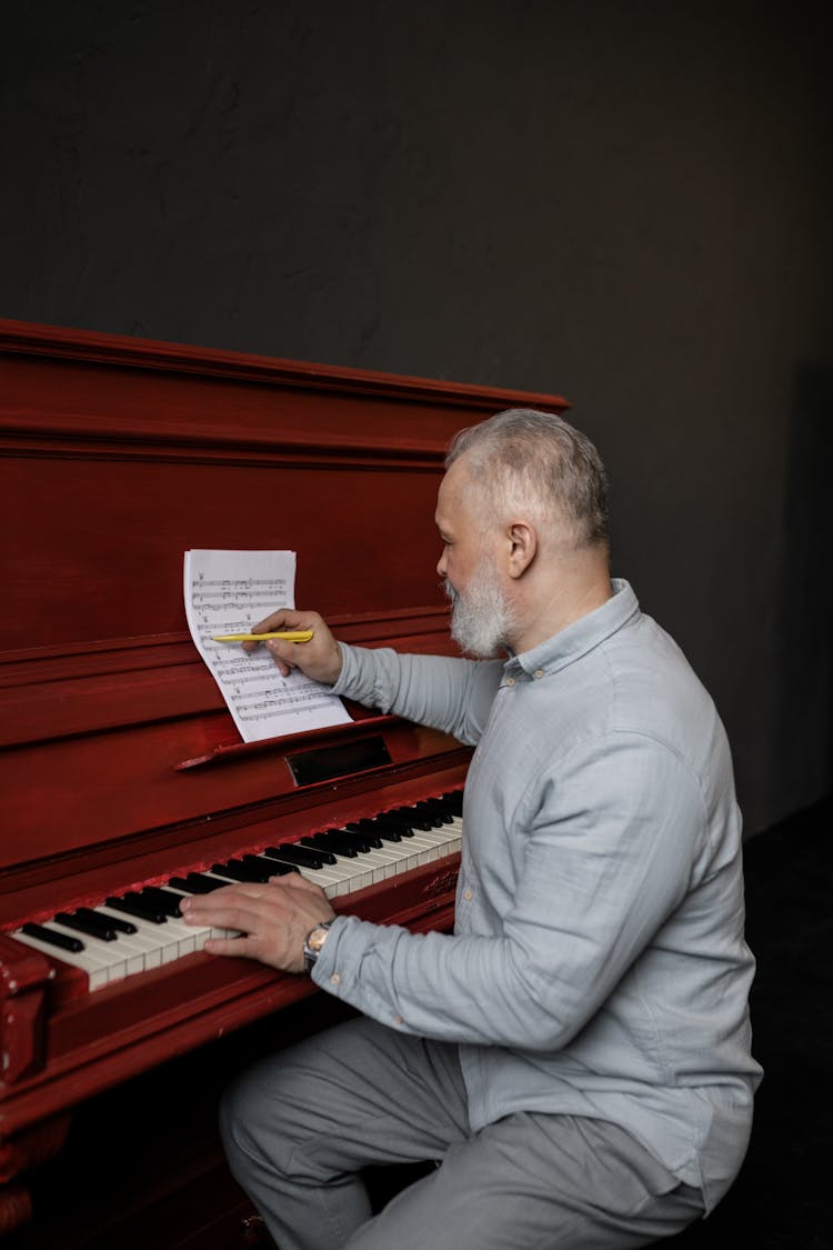 Elderly Man In Gray Long Sleeves Writing In A Sheet Music