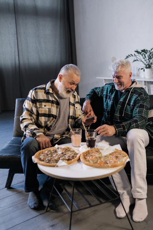 Elderly Men Laughing while Looking at a Smartphone