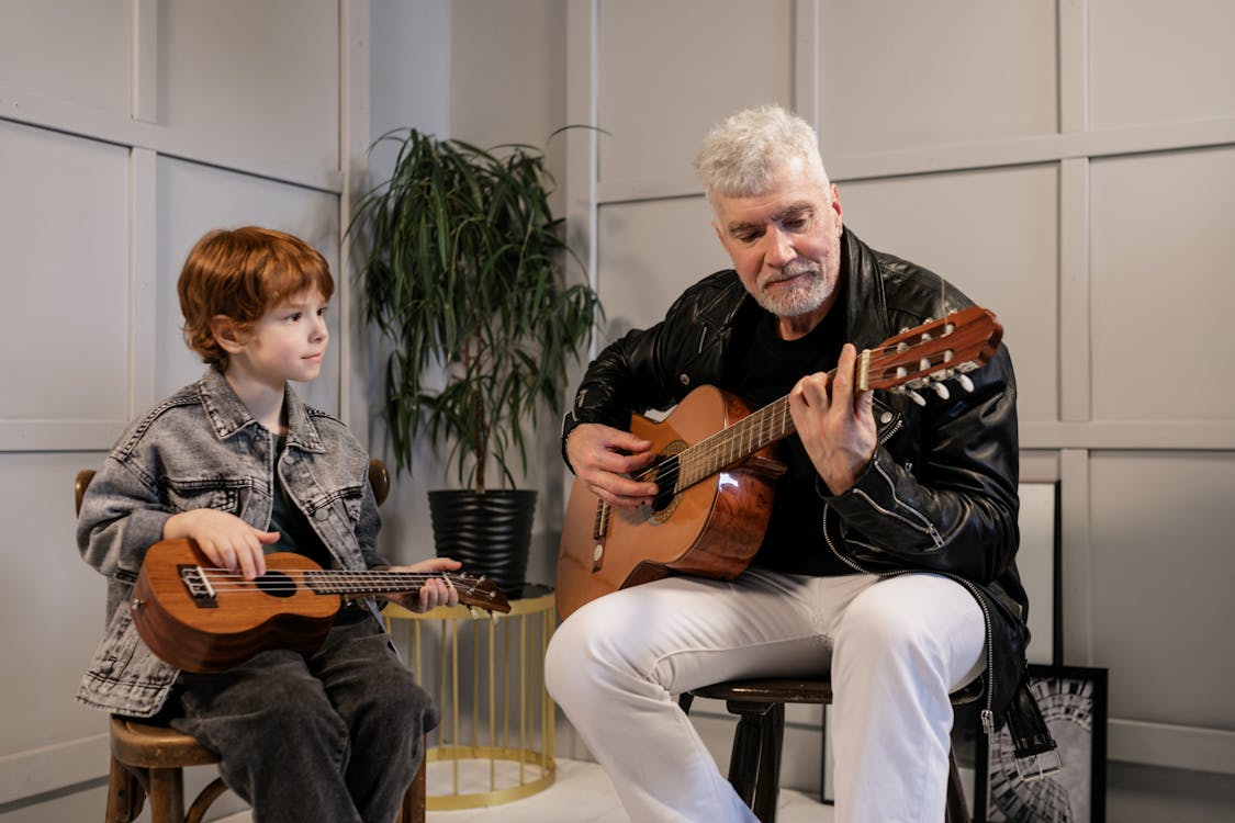 Free Grandson Observing His Grandfather Play the Guitar Stock Photo