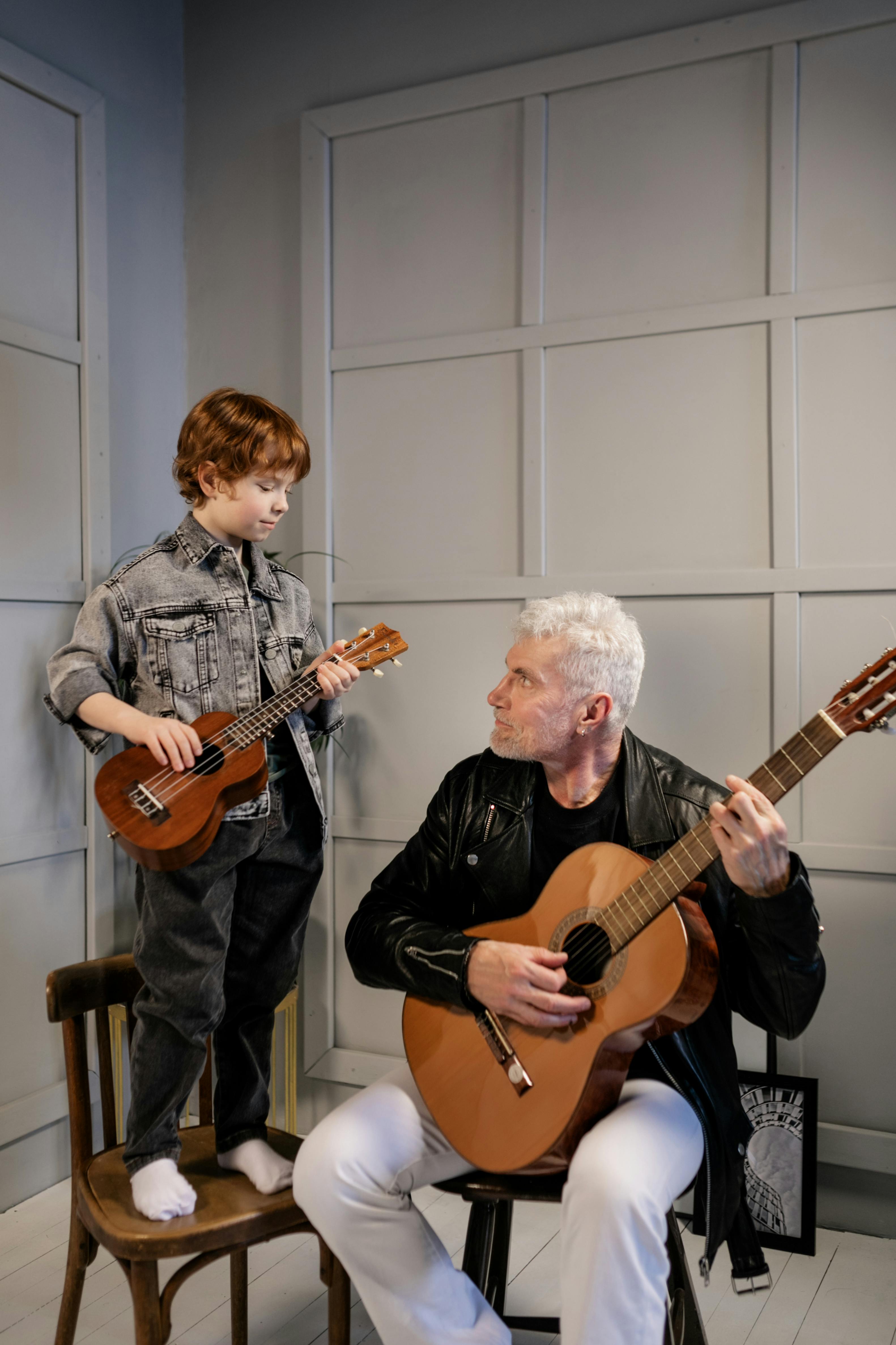 Free Grandfather Looking at His Grandson Play the Ukulele Stock Photo