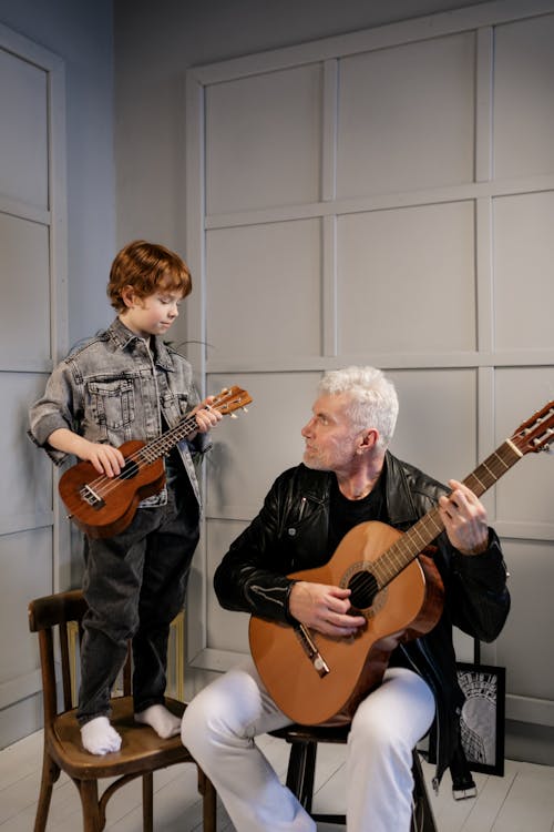 Grandfather Looking at His Grandson Play the Ukulele