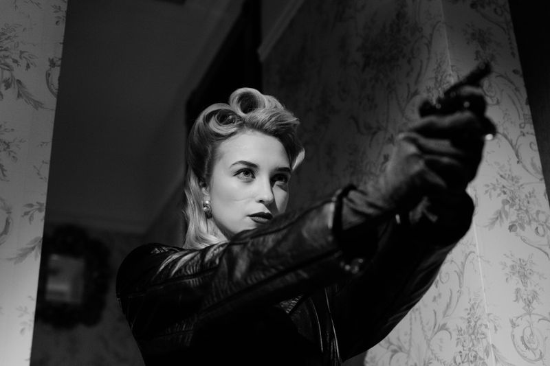 A striking monochrome portrait of a woman in vintage fashion, exuding mystery and elegance.