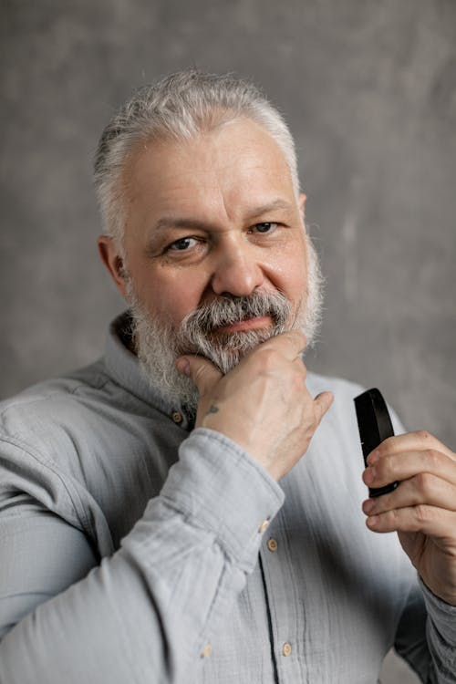 Elderly Man in Gray Dress Shirt Touching His Beard