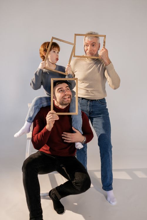 Free Three generations enjoy a playful moment together with picture frames in a studio setting. Stock Photo
