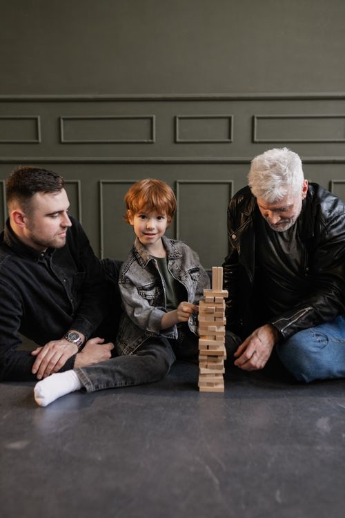 Free A boy, father, and grandfather enjoy playing Jenga together indoors, highlighting family bonding. Stock Photo