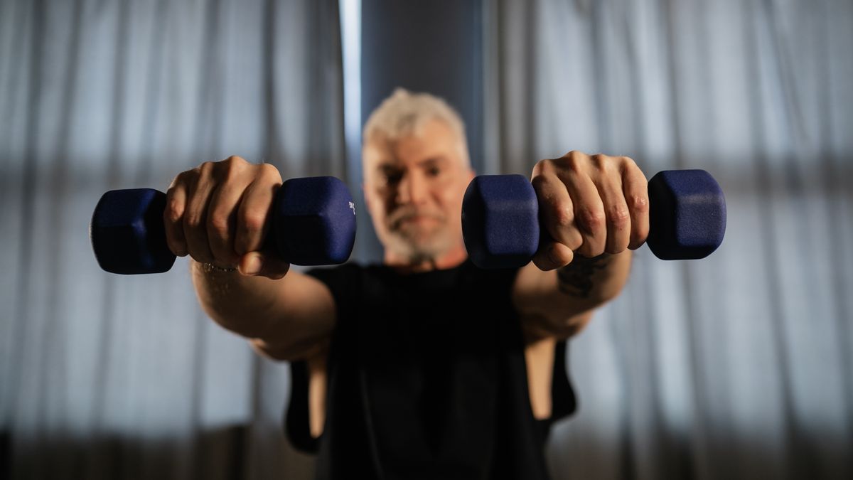 Senior man lifting dumbbells at home, embodying strength and active living.