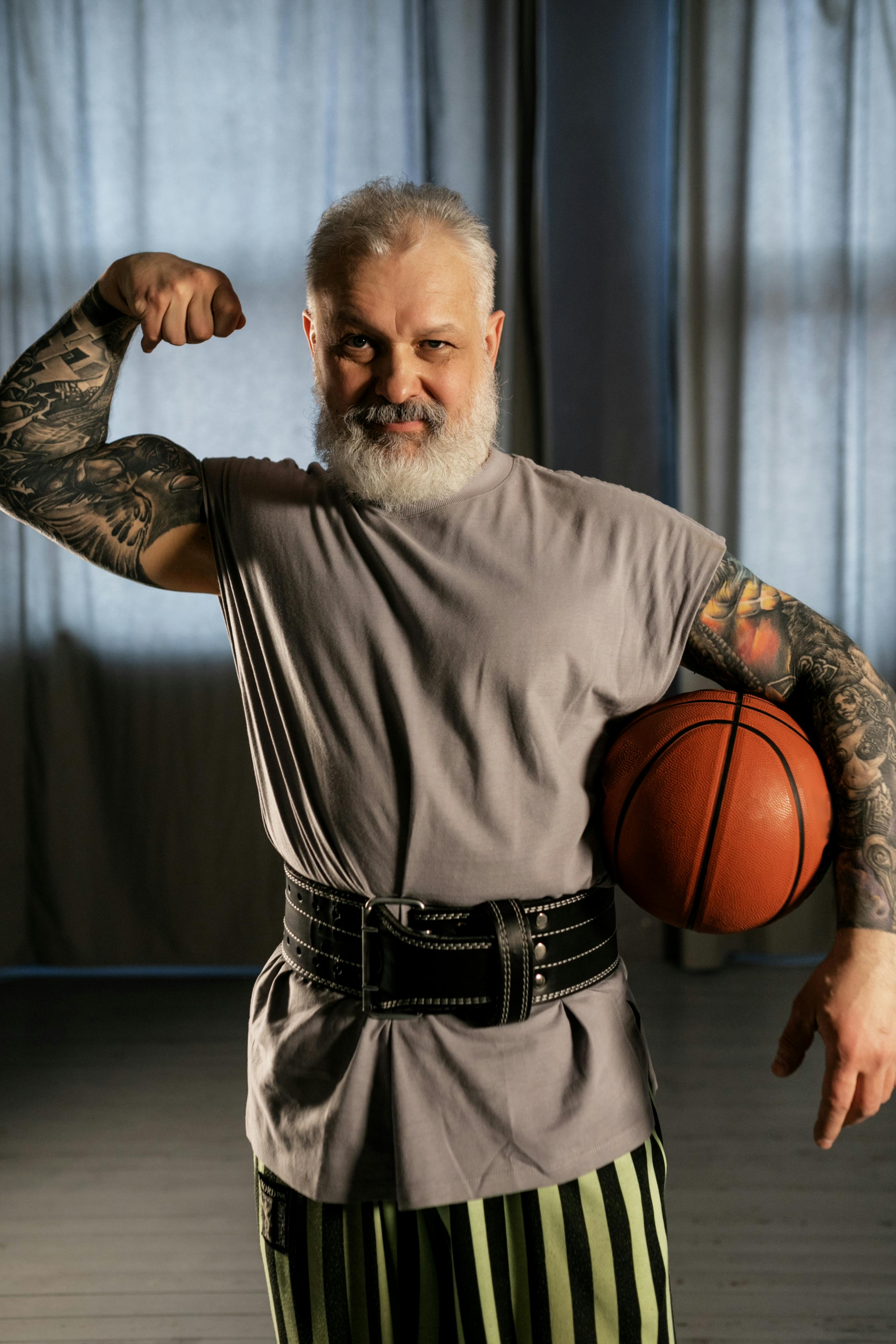 elderly man showing off his muscles while holding a basketball