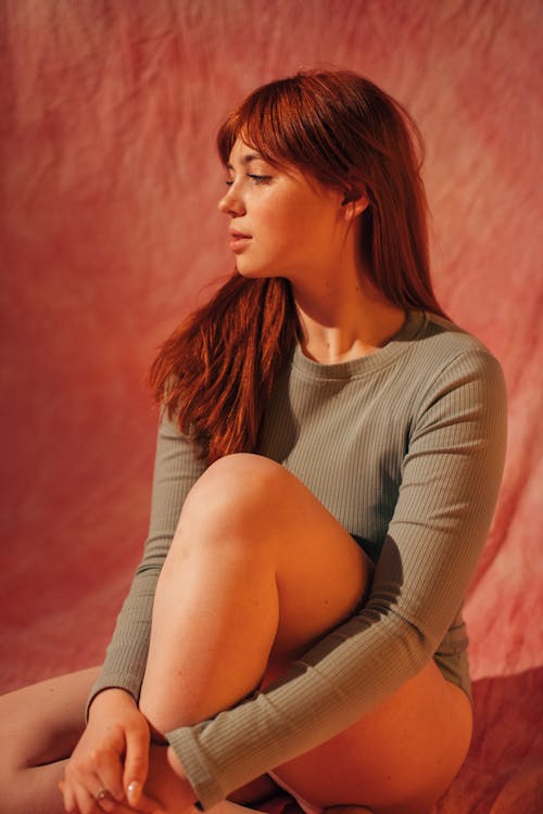 Woman in Gray Long Sleeves Looking Away While Sitting on the Floor 