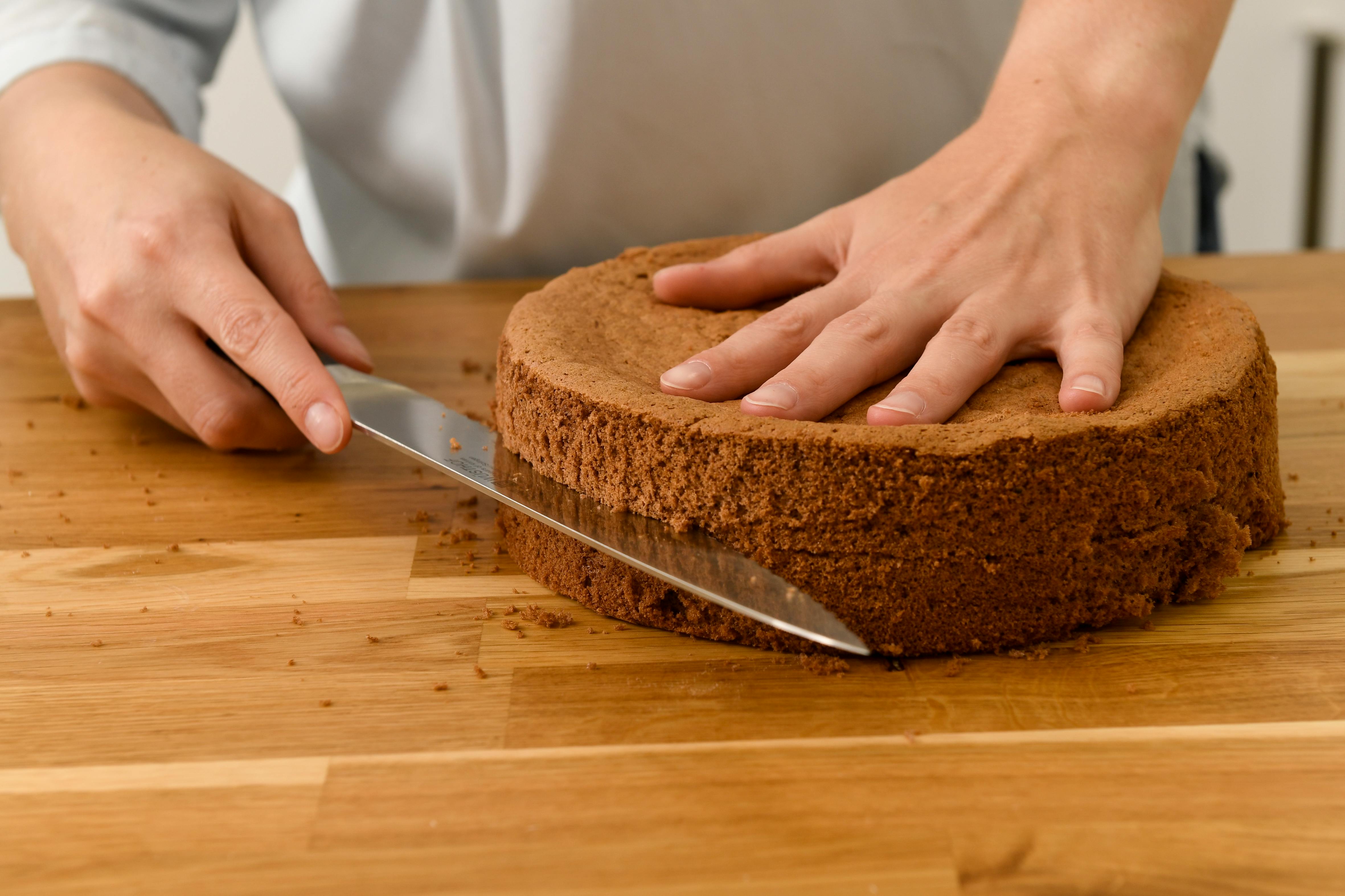 Person Slicing a Whole Cake in Half · Free Stock Photo