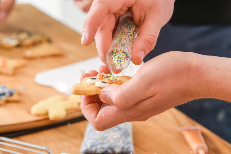 Person Adding Sprinkles On A Cookie