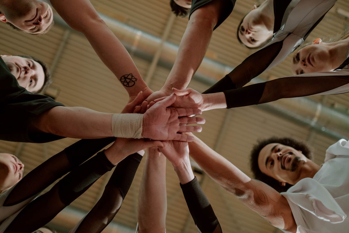 A diverse group of people joining their hands together in a gesture of unity and mutual support.