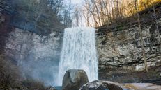 Scenic waterfall falling down rocky ravine in autumn forest
