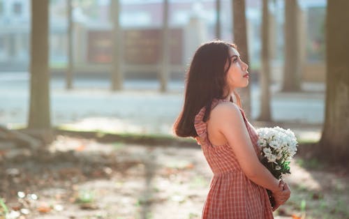 Gratis Wanita Mengenakan Gaun Tanpa Lengan Warna Coklat Mengusung Buket Bunga Putih Foto Stok