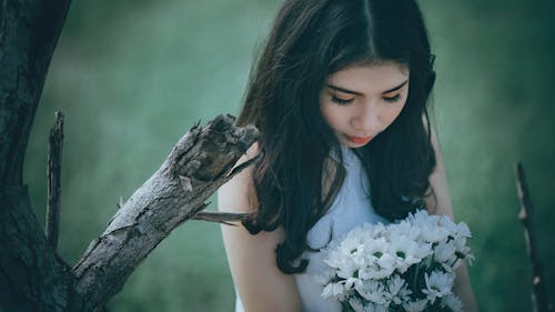 무료 흰 꽃 꽃다발을 들고 흰 고삐 탑을 입고 여자 스톡 사진