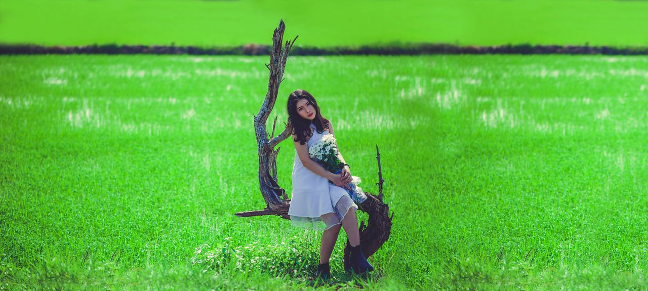 a young woman in a white dress with a bouquet in a lush green field em