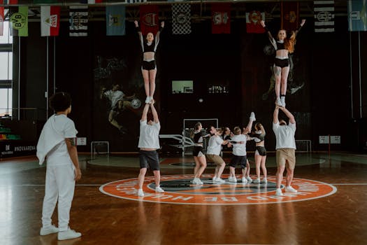 Cheerleading team practicing stunts inside a gymnasium, showcasing teamwork and athleticism.