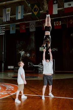 Athletic cheerleaders perform complex stunts in an indoor gym during practice session.