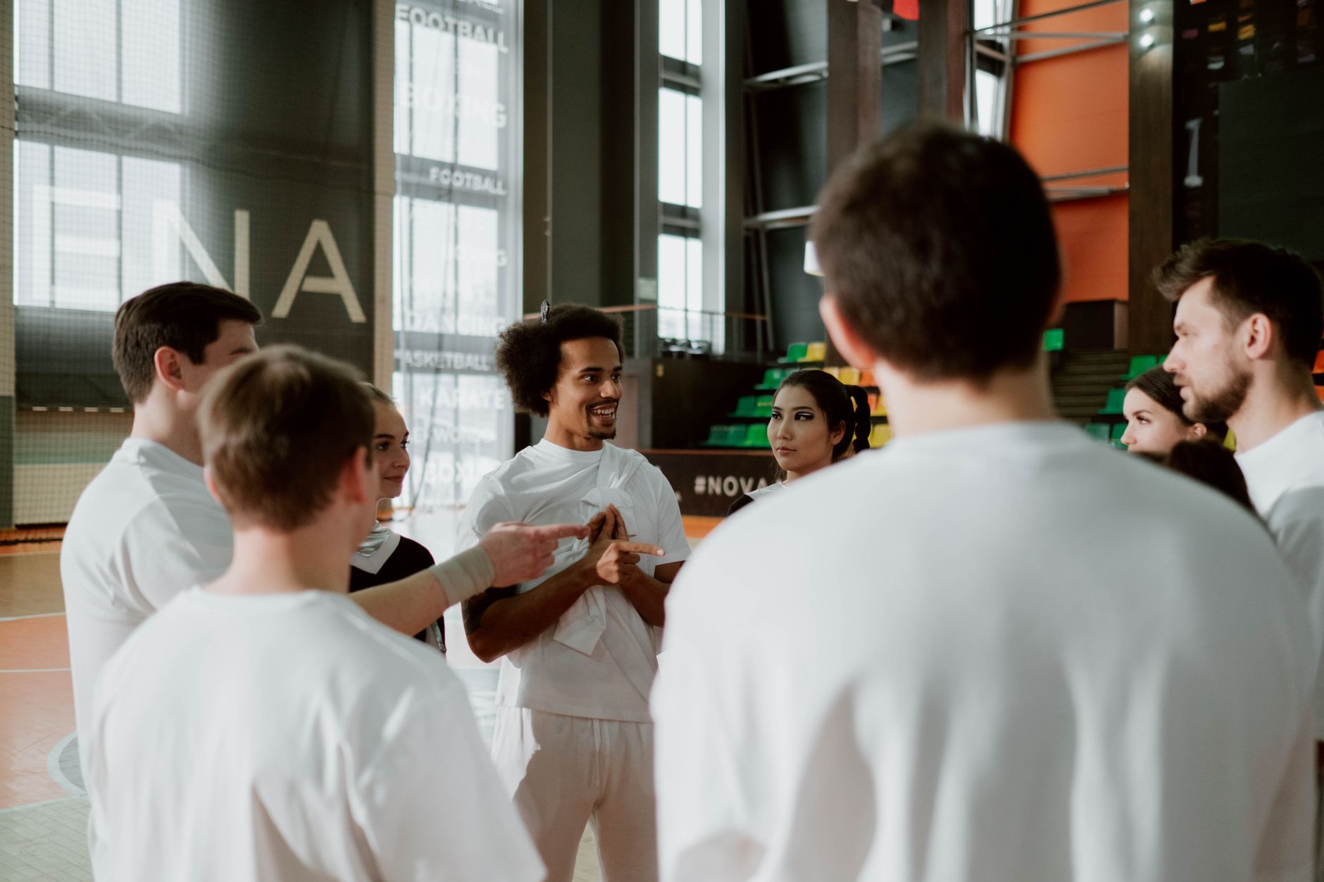 A group of athletes in a motivational huddle in an indoor sports gym.