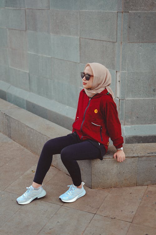 Young Woman in Sunglasses, Hijab and Sports Clothing Sitting on a Curb 