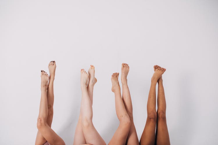 A Group Of People Lying Down With Legs Up On Air