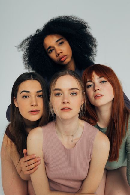 A diverse group of women posing elegantly in a studio setting.