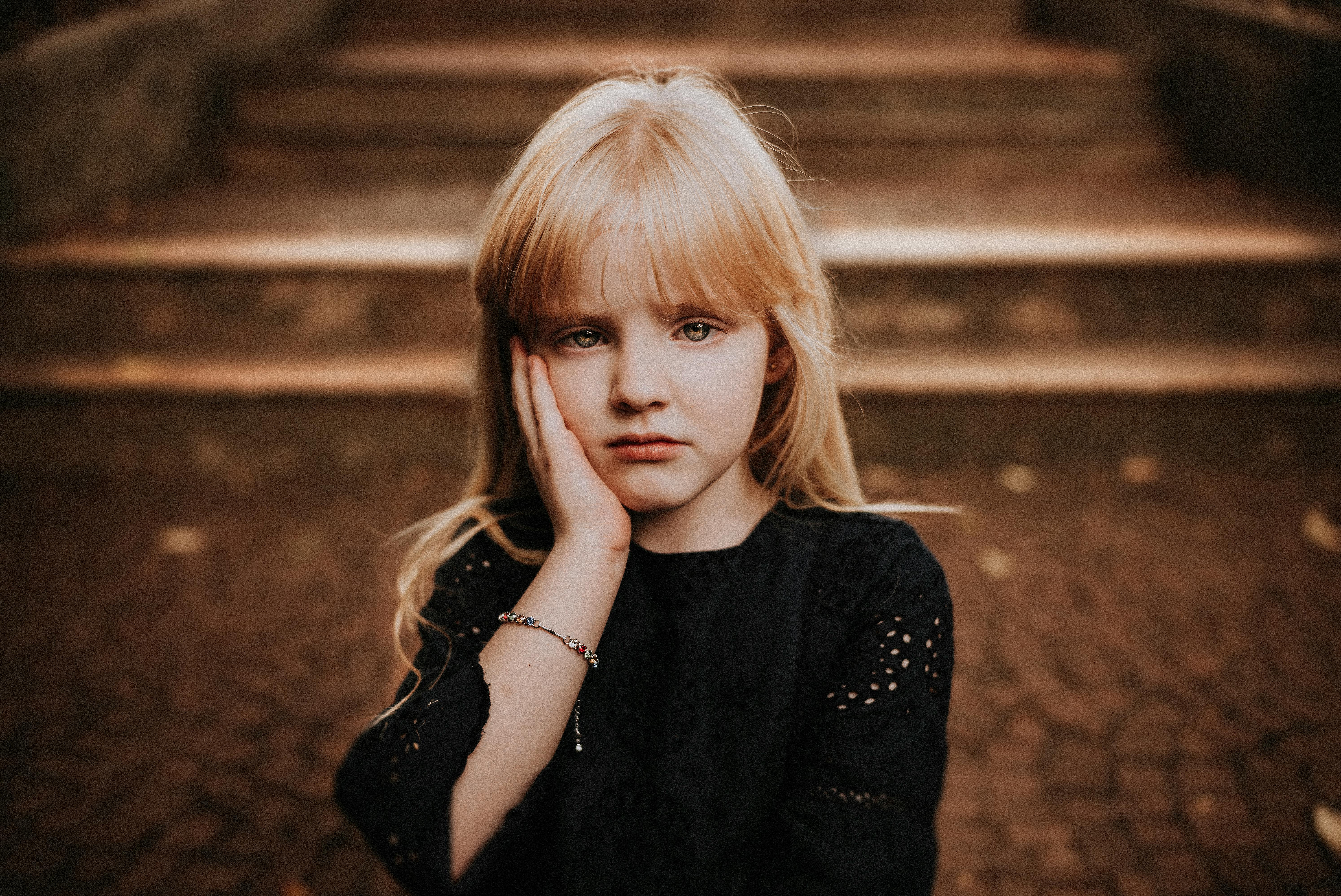 sad little girl touching face and looking at camera in autumn park