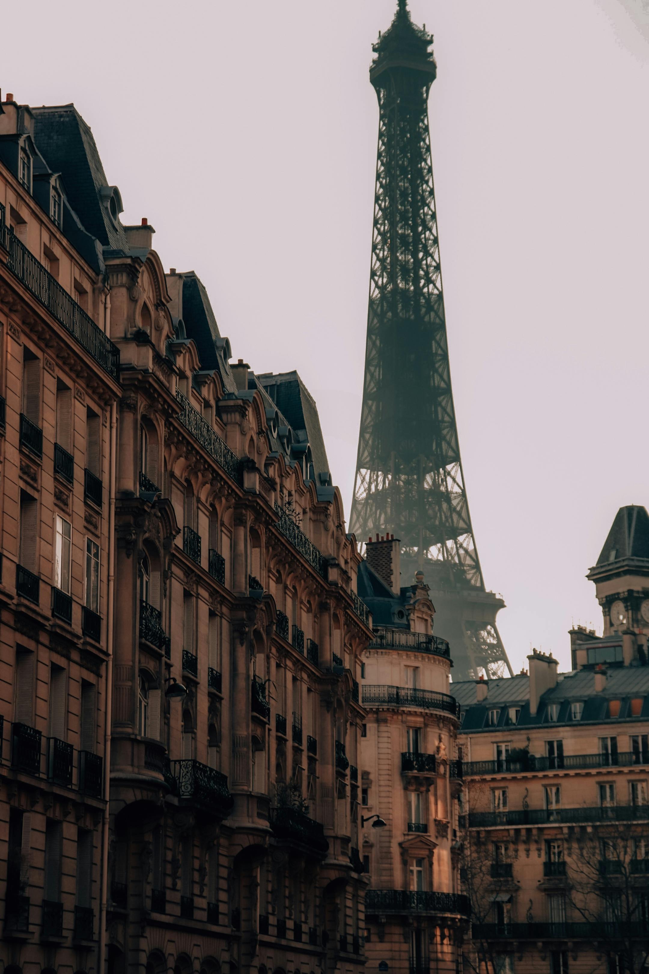 View of the Eiffel Tower framed by classic Parisian buildings under a gloomy sky.