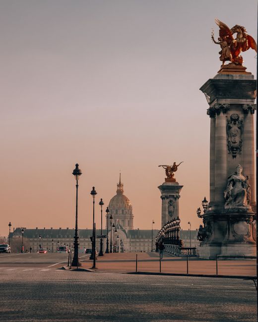 Stunning sunset over Pont Alexandre III with ornate sculptures and Paris skyline.