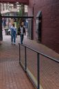 Man in Blue Denim Jeans Walking on Sidewalk