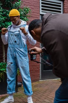Stylish urban photoshoot featuring a model in denim overalls and yellow beanie outdoors.