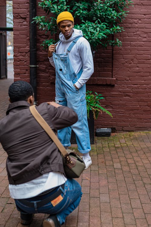 A Person Taking Picture of a Man in Denim Jumper and Yellow Knit Cap
