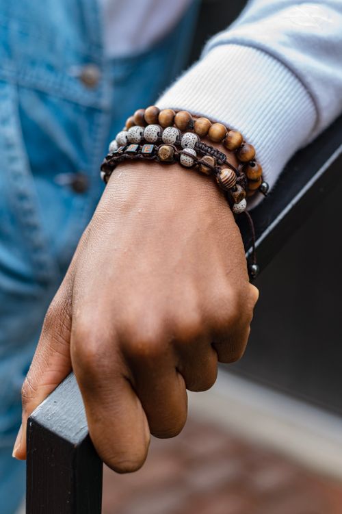 Free Hand holding railing adorned with multiple beaded bracelets in a casual setting. Stock Photo