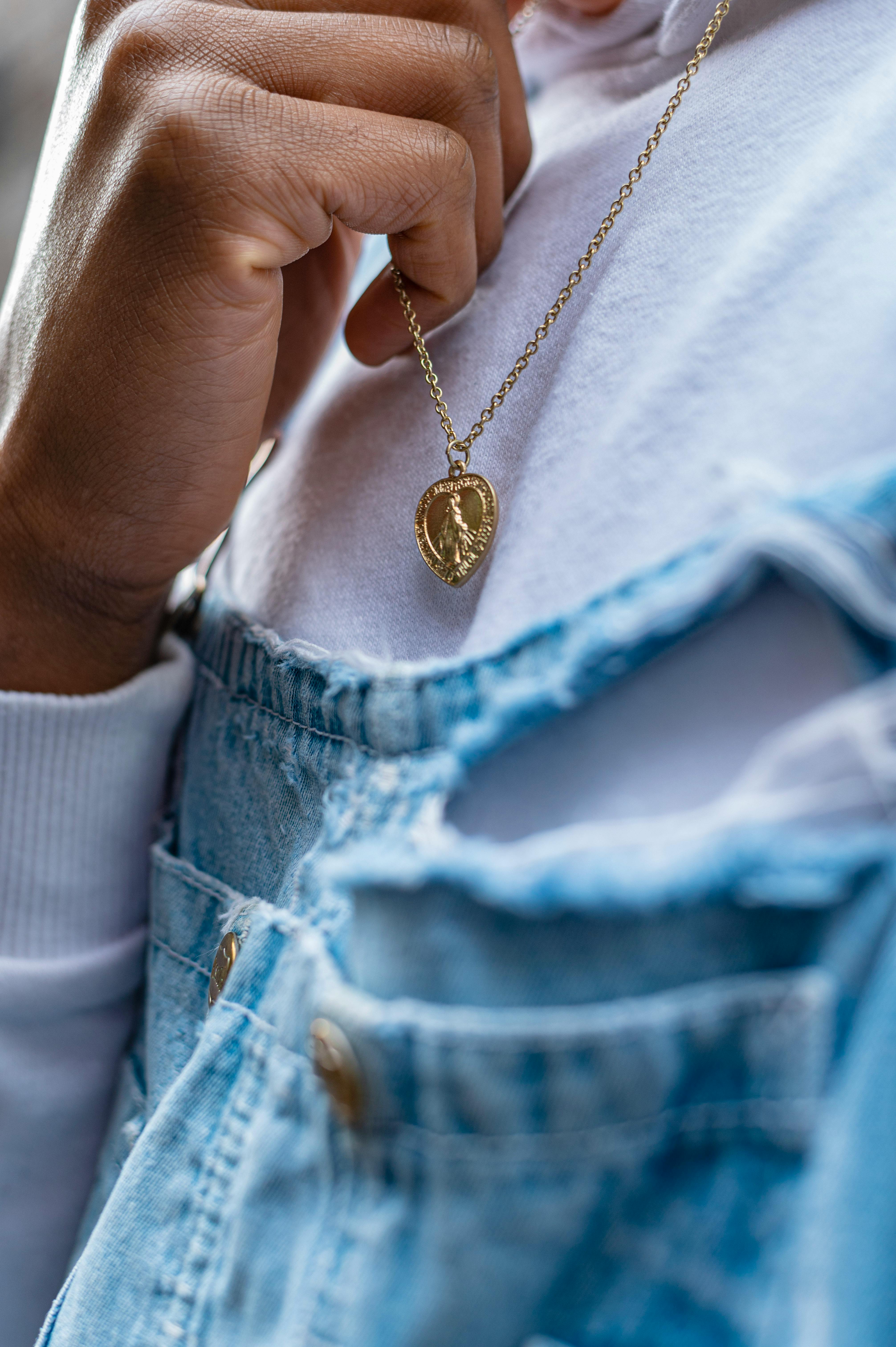 a close up shot of a person holding a gold necklace