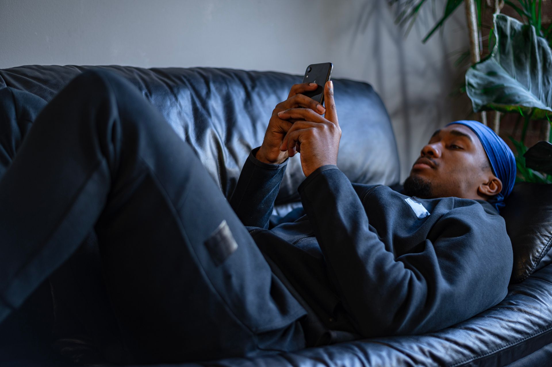 Man in Black Jacket Lying on Couch using Smartphone