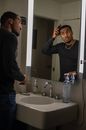A Man Brushing his Hair in front of the Mirror
