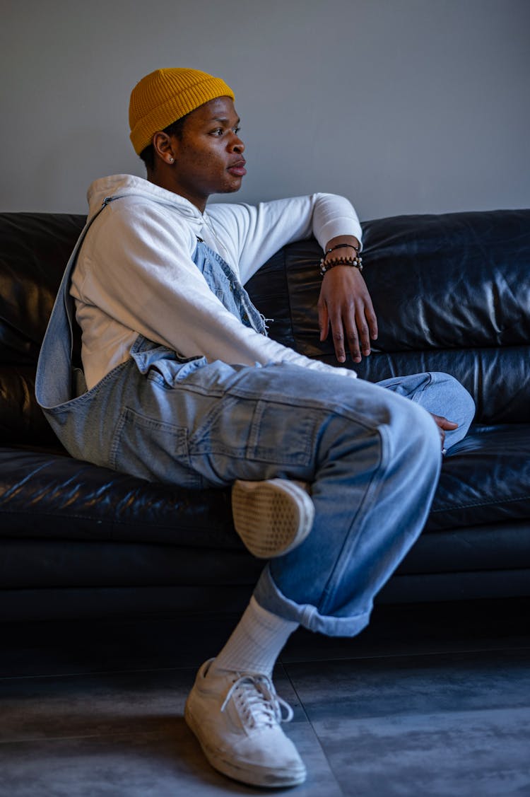 A Man In Overalls Sitting On A Couch 