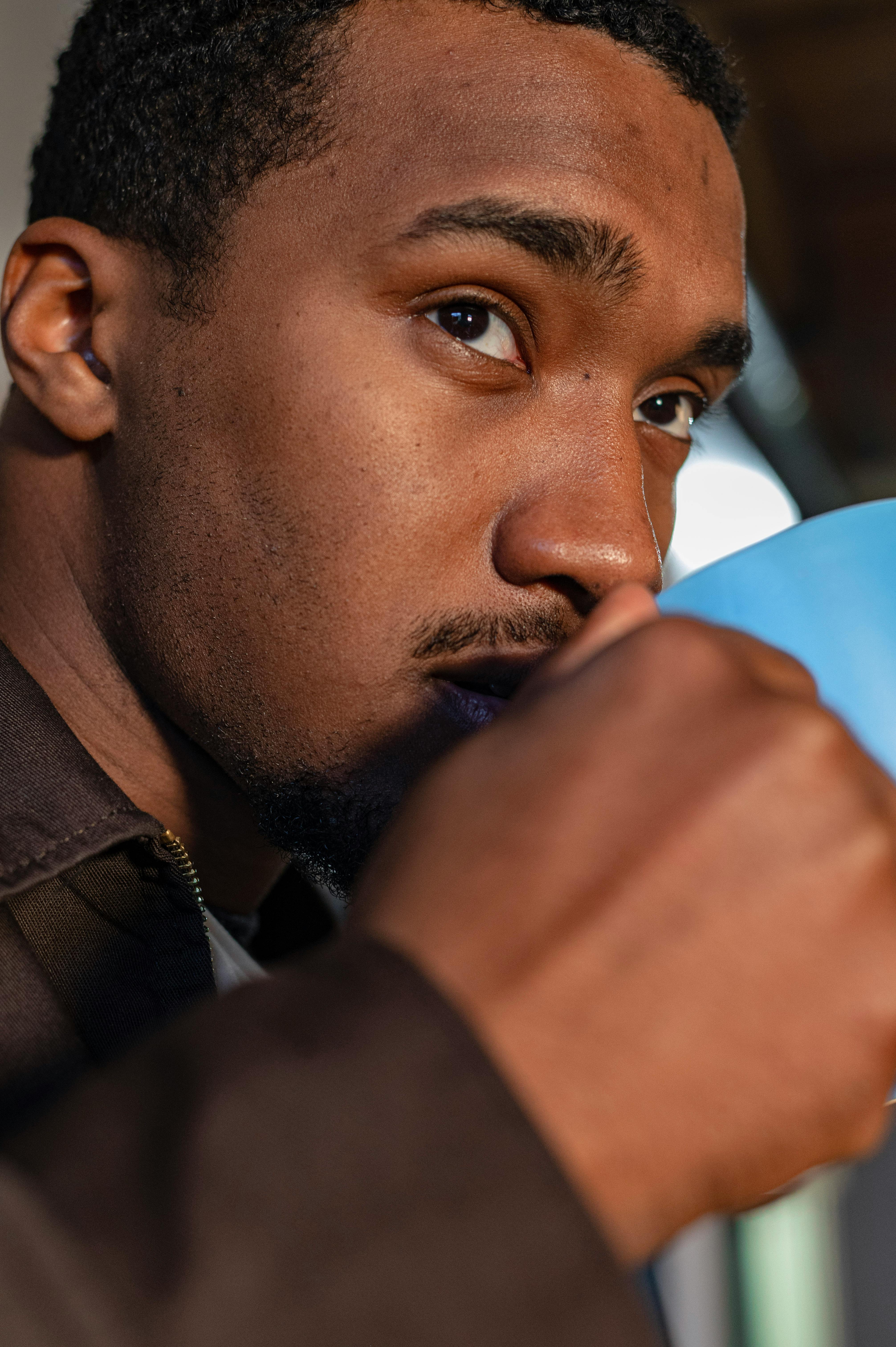 Close-up of a man sipping a warm drink from a mug at home.