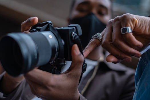 A close-up view of hands holding and adjusting a DSLR camera indoors.