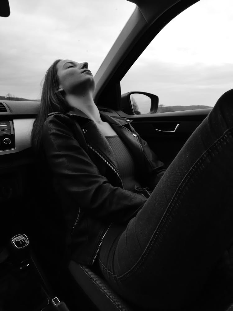 Grayscale Photo Of A Woman Leaning Back On A Dashboard