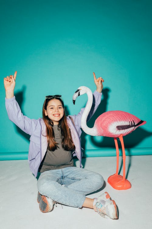 Free Girl Posing Beside a Flamingo Figurine Stock Photo