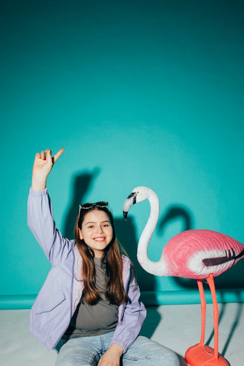 Free Girl Sitting Beside a Flamingo Figurine Stock Photo