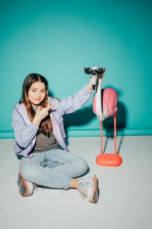 Free Girl Posing Beside a Flamingo Figurine Stock Photo