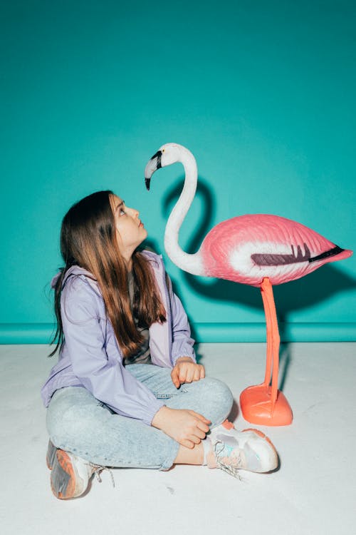 Free Girl Looking at a Flamingo Figurine Stock Photo