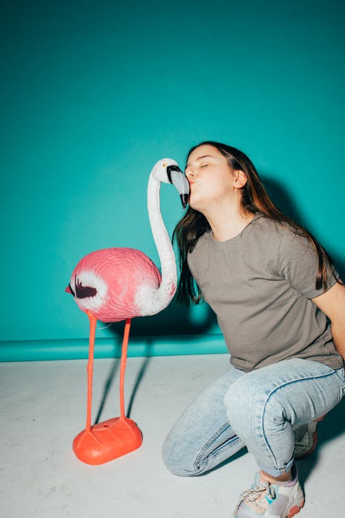 Free Girl Posing Beside a Flamingo Figurine Stock Photo