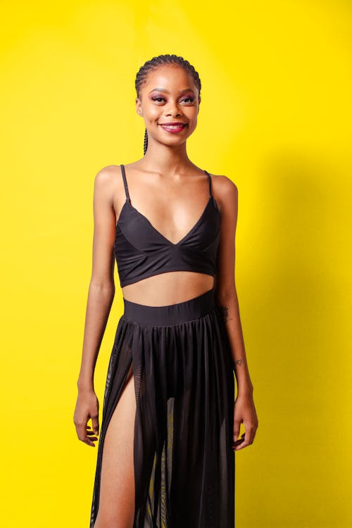 Free A Woman Posing in a Black Outfit with a Yellow Background Stock Photo