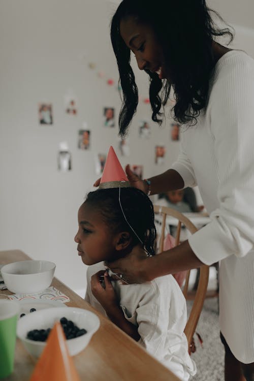 Free A Woman Putting a Party Hat on Her Child  Stock Photo