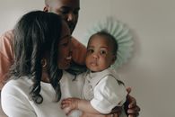 Man in White Dress Shirt Carrying Baby in White Dress